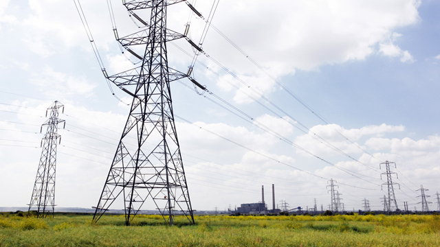 Electricity pylons with transmission lines in fields with Tilbury B Power Station in the background