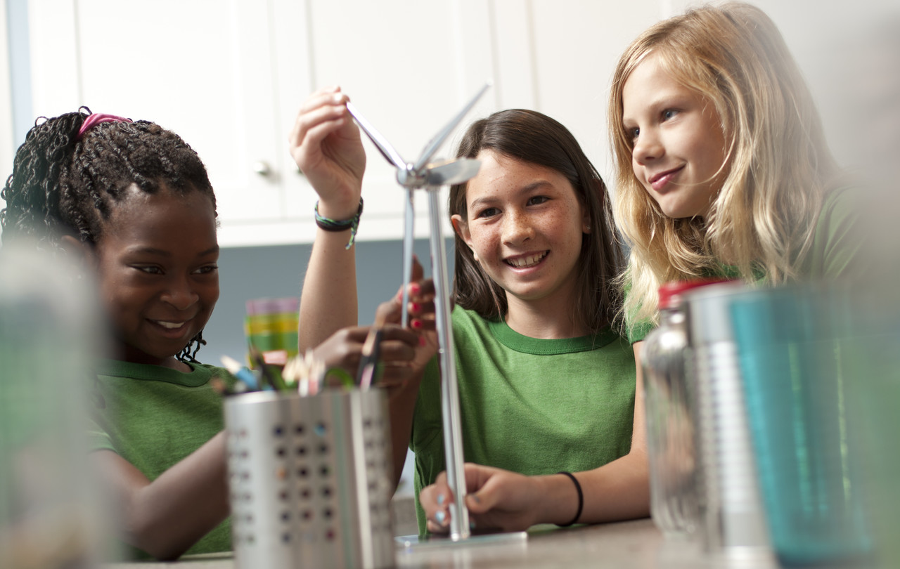 Three children play with a miniature wind turbine